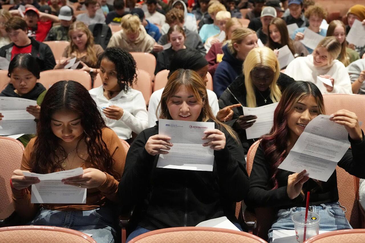 A photo of three highschool seniors looking at their Minnesota Direct Admissions results.
