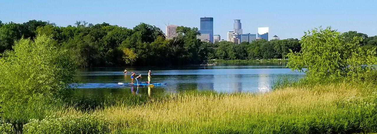 A landscape image of people paddle boarding across the Lake of the Isles.