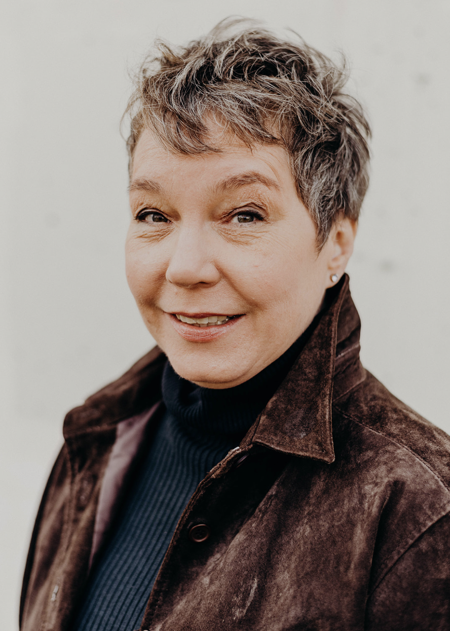 Photo of Mary wearing a brown jacket and navy blue top.
