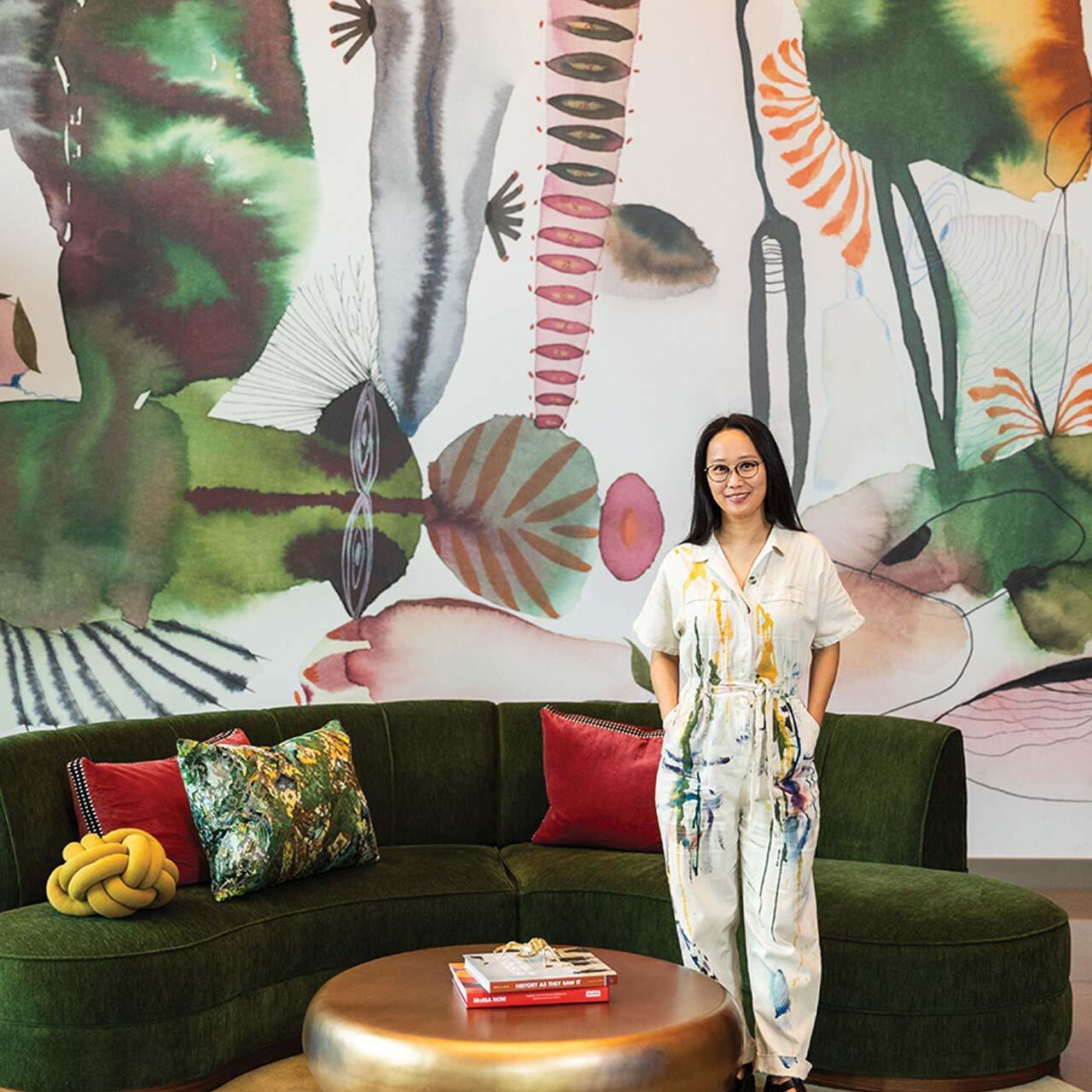 Suyao Tian standing in front of a large abstract watercolor wallpaper she designed.
