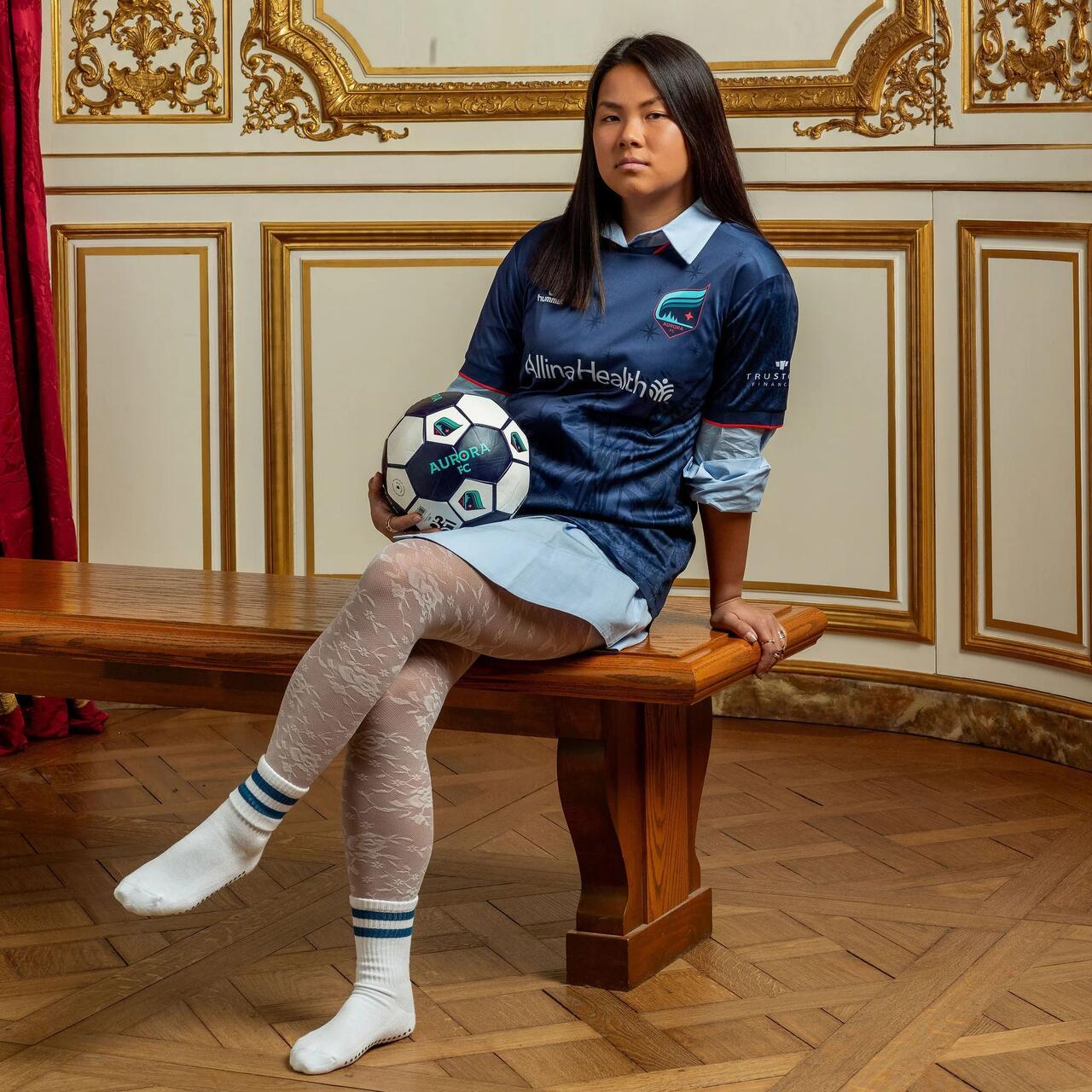 A photo of a woman wearing the Flora Jersey in a MIA historical room.