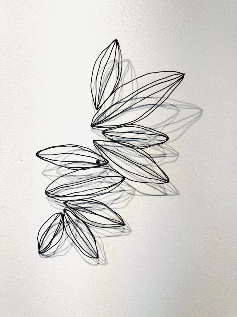 A wire sculpture that resembles seeds titled In Balance 2 by Jodi Reeb.
