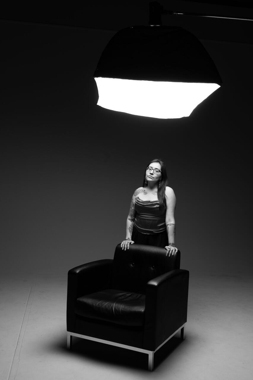 Portrait of someone standing behind a leather chair.