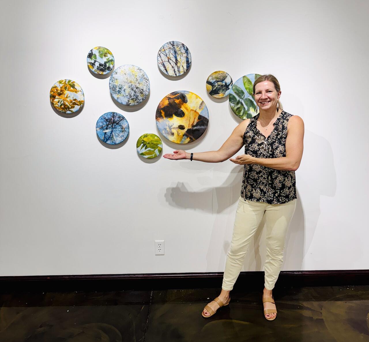 Jodi Reeb standing infront of some of her circular paintings.