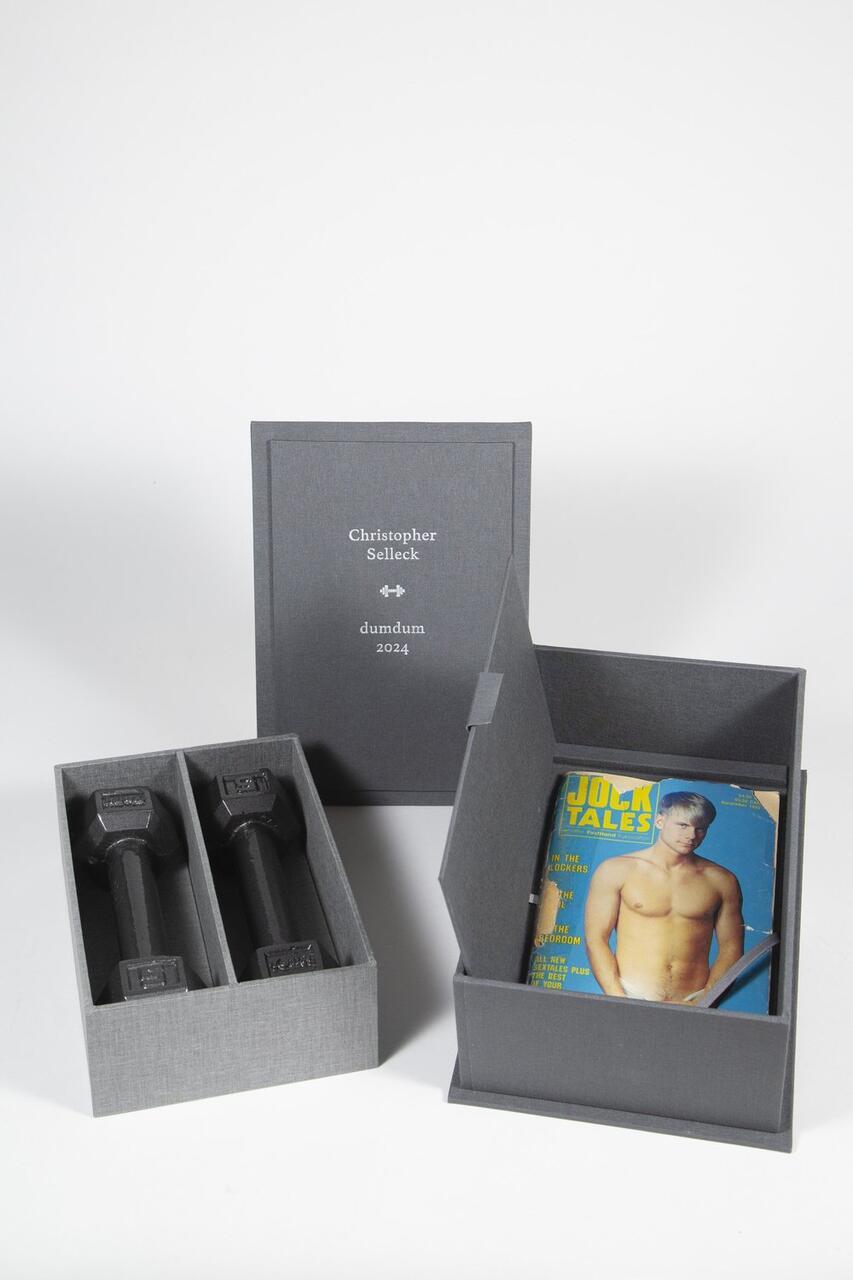 Dumdum by Christopher Selleck. The work is a grey box in the shape of a book, which opens to two dumbells, and a gay magazine hidden underneath.