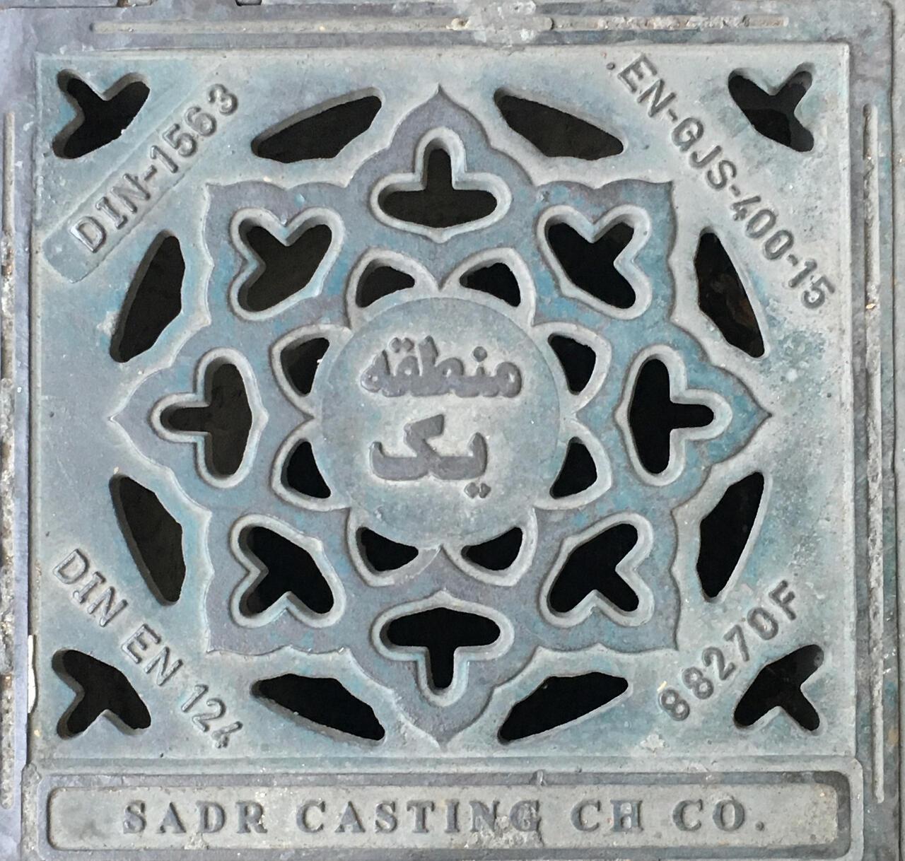 A perian manhole cover with ornate details and text.