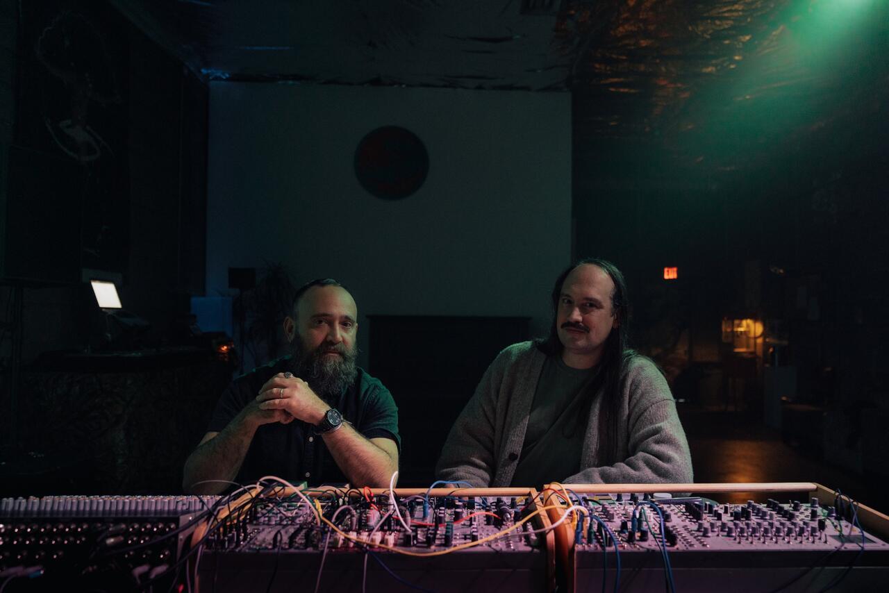 Musical group Yellow Swans sitting behind a synth.